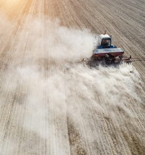 Farmer seeding, sowing crops at field. Sowing is the process of planting seeds in the ground as part of the early spring time agricultural activities.